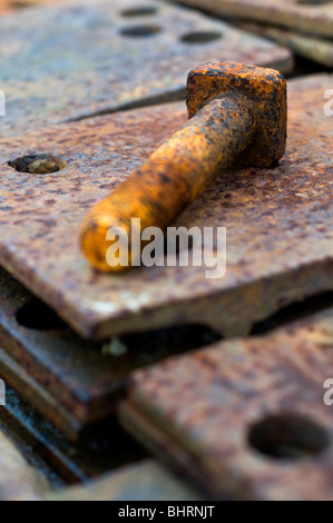 A rusty bolt on a pile of rusting metal plates Stock Photo