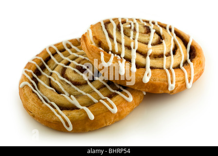 Two cinnamon danish pastry swirls, with icing drizzled across them, isolated on a clean white background. Stock Photo