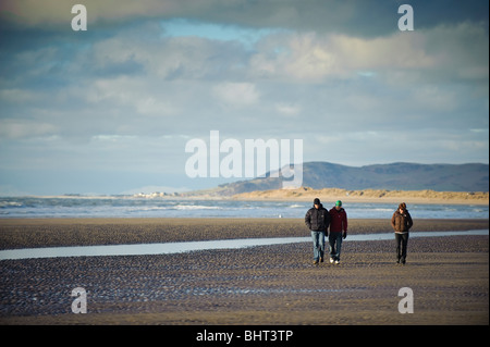 three people walking on the beach at the Dyfi Ynyslas national nature reserve, near Borth, Ceredigion, Wales UK Stock Photo