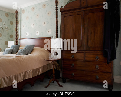 Large mahogany wardrobe in townhouse bedroom with pale gray stylized floral wallpaper Stock Photo