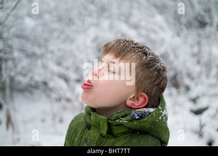 Small boy trying to catch snowflakes on tongue Stock Photo