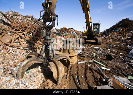 Excavating machine, with large grapple claw, at scrap metal yard. Stock Photo