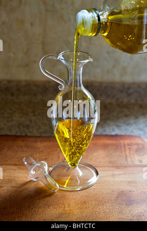 Olive oil being poured into a salad dressing jug Stock Photo