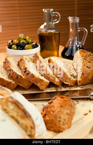 Sliced rustic bread and bread knife with olives, olive oil and balsamic vinegar Stock Photo