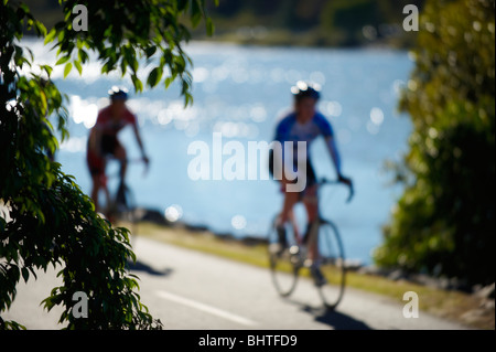 Riding bicycles beside river Stock Photo