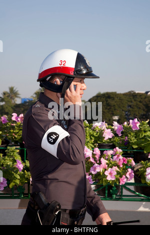 Uniformed Thai Policeman holding police radio, wearing pollution mask in Chiang Mai, Thailand, Asia Stock Photo