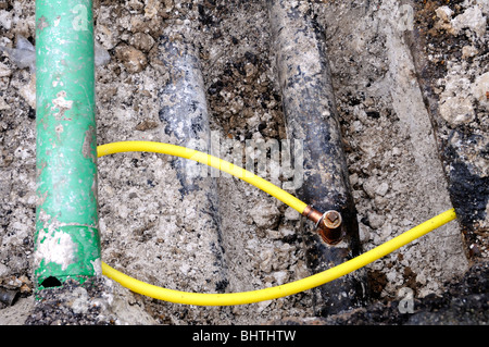 New yellow plastic domestic pipe is temporarily connected to the old main metal gas pipe. The green pipe is for fiber optics. Stock Photo