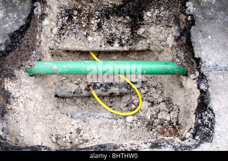 New yellow plastic domestic pipe is temporarily connected to the old main metal gas pipe. The green pipe is for fiber optics. Stock Photo