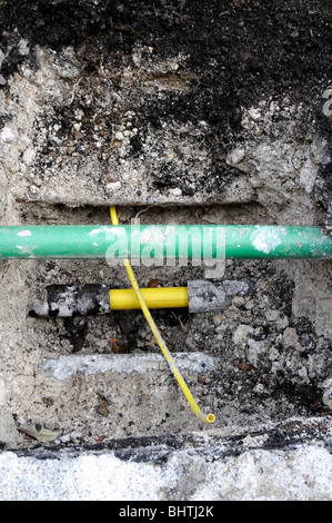 New yellow plastic domestic gas pipe ready to be connected to the new main pipe. The green pipe is for fiber optics. Stock Photo