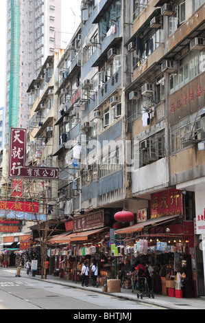 Apartments, clothes hanging from windows, above shops selling lanterns, clothes, household items. Queen's Road West, Hong Kong Stock Photo