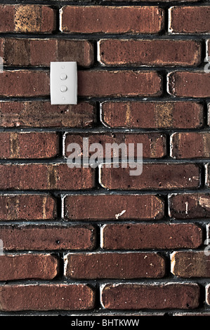 Grunge styled brick wall showing lots of texture with a double light switch on it. Stock Photo
