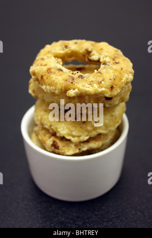 A side order of onion rings displayed in a small white ramekin dish Stock Photo