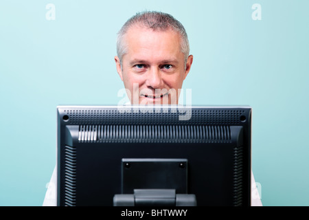 Mature man working at a computer looking over the screen Stock Photo