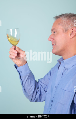 Man holding up a glass of white wine checking for clarity and quality. Stock Photo