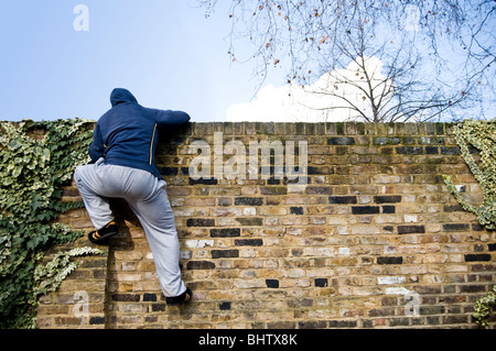 A young man climbing over a wall Stock Photo