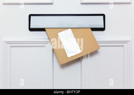 Brown envelope in a front door letterbox blank window for you to add your own name and address details. Stock Photo
