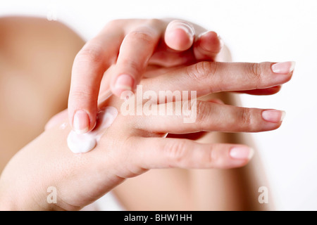 Young woman cares about her hands, applying cream on them. Stock Photo