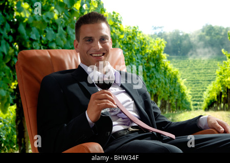 Young man in business suit sitting with glass of red wine Stock Photo