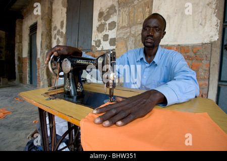 Man using an old sewing machine to stitch fabric in Uganda Stock Photo