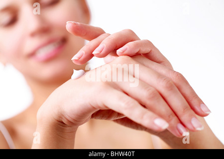 Smiling young woman applies cream on her hands. Stock Photo