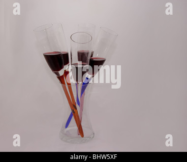 This photo shows a glass bouquet of red wine in glasses in a glass vase on a light background. Stock Photo