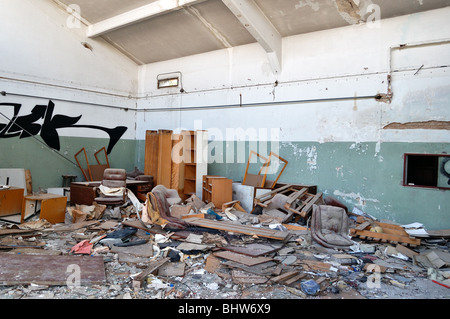 Vandalized office equipment and debris in a partially demolished abandoned factory. Stock Photo