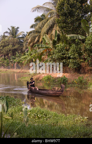 India, Kerala, Alappuzha, Chennamkary, western visitor paddling wooden canoe through backwaters Stock Photo