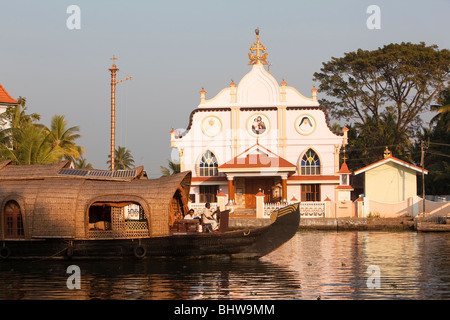 India, Kerala, Alappuzha, Chennamkary, kettuvallam houseboat passing St Joseph’s Catholic church Stock Photo