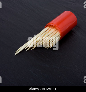 Cocktail Sticks spilling from container on dark slate background. Stock Photo