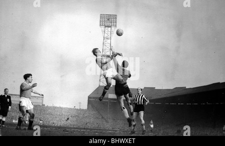 Action during the league match between Manchester United and Newcastle United February 1959 Action at Old Trafford in 1959. Manchester United’s Bobby Charlton - from the Ashington Milburn stock - leaps with Newcastle goalkeeper Bryan Harvey. Jimmy Scoular looks on. Stock Photo