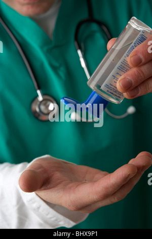 man wearing medical scrubs and stethoscope pouring alcohol gel into his hands using hand sanitiser sanitizer in healthcare anti virus bacteria Stock Photo