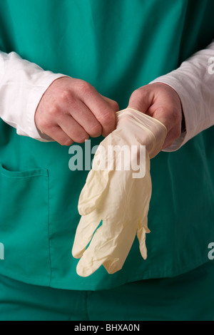 man wearing medical scrubs putting on a of rubber gloves Stock Photo
