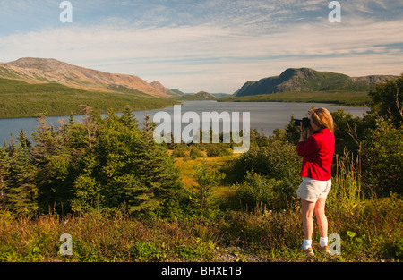 Newfoundland, Gros Morne National Park, Woman taking picture of lake near White Point, UNESCO World Heritage Site Stock Photo