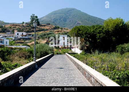 A pedestrian walkway in the village of Lingua and the dormant volcano of Monte Fossa delle Felci, on the Aeolian island of Salina, Sicily, Italy. Stock Photo