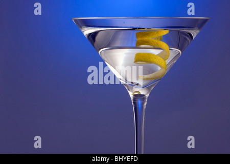 Spotlighted Straight up Martini with Lemon Twist Garnish on Blue background Stock Photo
