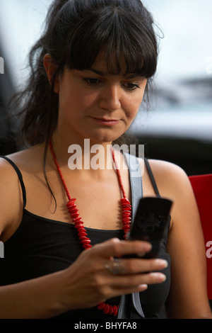 mid twenties hispanic woman reading a text message from a mobile phone with sad face Stock Photo