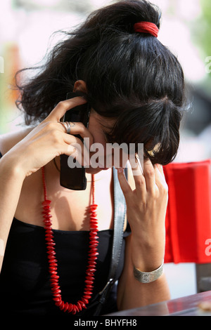mid twenties hispanic woman talking quietly on a mobile phone touching her forehead with her hand Stock Photo