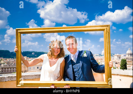 Bride and groom holding gold picture frame on wedding day in Rome, Italy Stock Photo