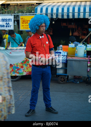 Funny man with blue hair hands out fliers at the chatuchak weekend market in Bangkok Thailand Stock Photo