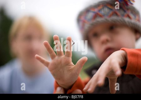Young boy looking at an inchworm crawling on his hand. Stock Photo