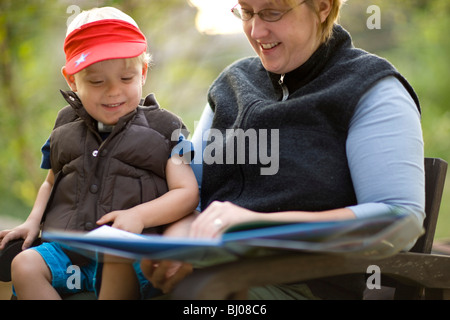 Mother and son reading a book outside. Stock Photo