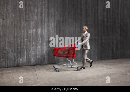 businessman pushing red shopping trolley Stock Photo