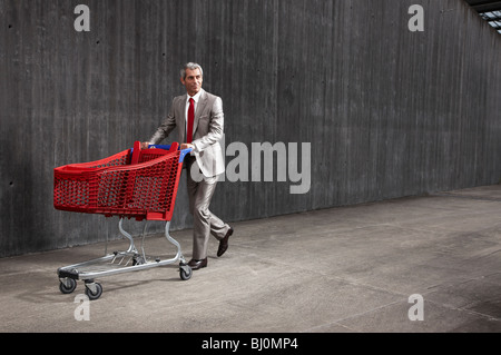 businessman pushing red shopping trolley Stock Photo