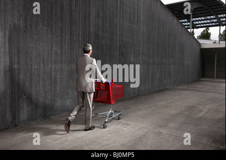 rear view of businessman pushing red shopping trolley Stock Photo