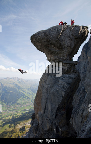 BASE jumping from a cliff with some friends. The ultimate kick to do an object jump with tracking pants into the deep valley. Stock Photo