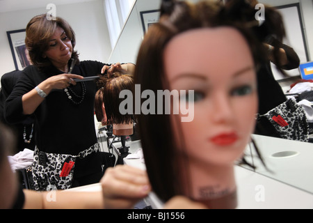 Woman studying hair dressing at college, practicing on a mannequin's head. Stock Photo