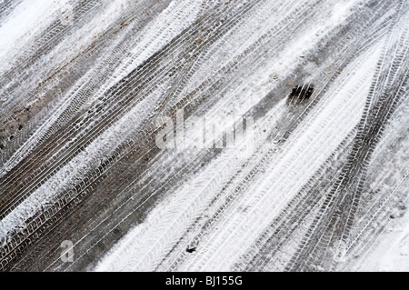 Melting car tracks on snow covered road - France. Stock Photo