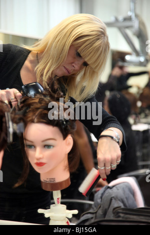 Woman studying hair dressing at college, practicing on a mannequin's head. Stock Photo