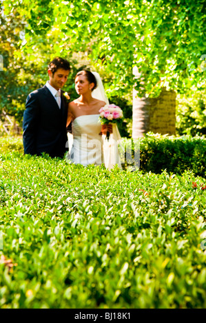 The bride and groom are walking in the park in the summer, hugging. The ...