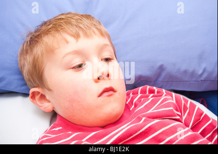 A MODEL RELEASED picture of a 6 year old boy laying down feeling ill in the uk Stock Photo